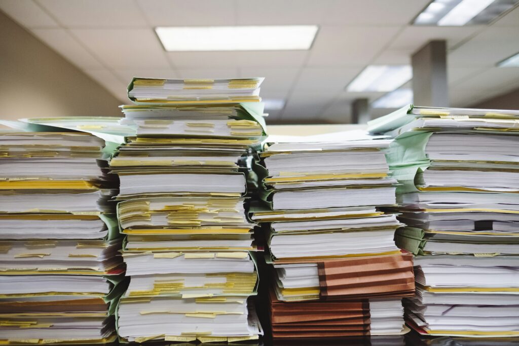 Pilas de documentos en papel representan la falta de Certeza Operativa en procesos manuales.